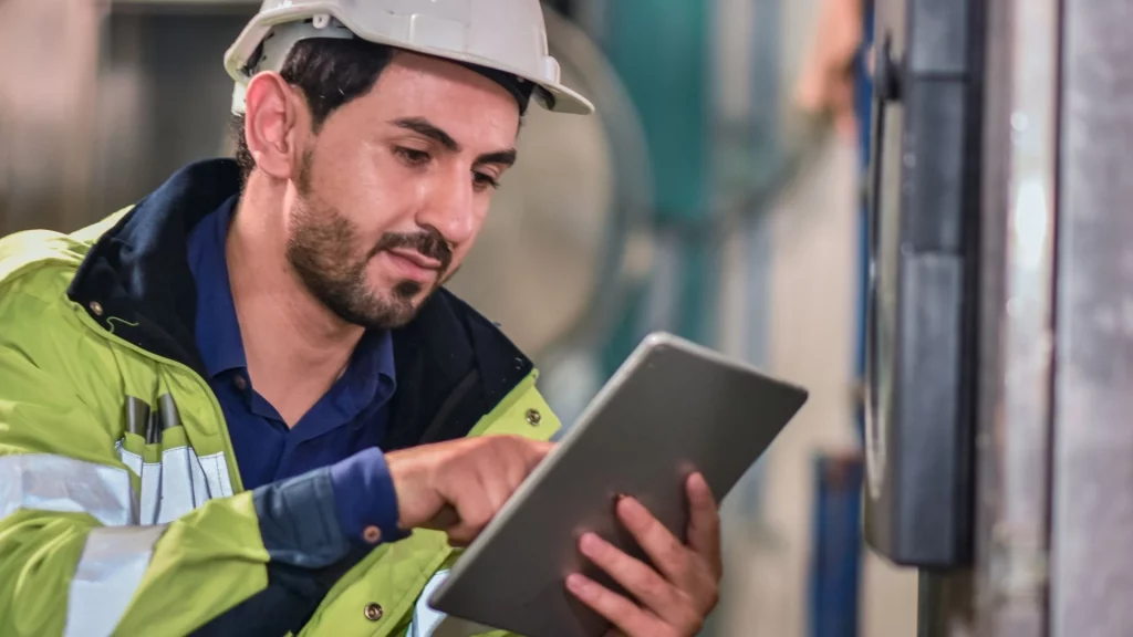 Industrial worker using a digital tablet for machinery monitoring in a manufacturing facility